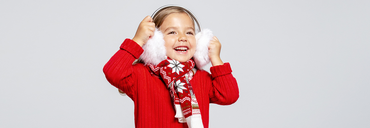 A young child in a red sweater wearing white earmuffs. 