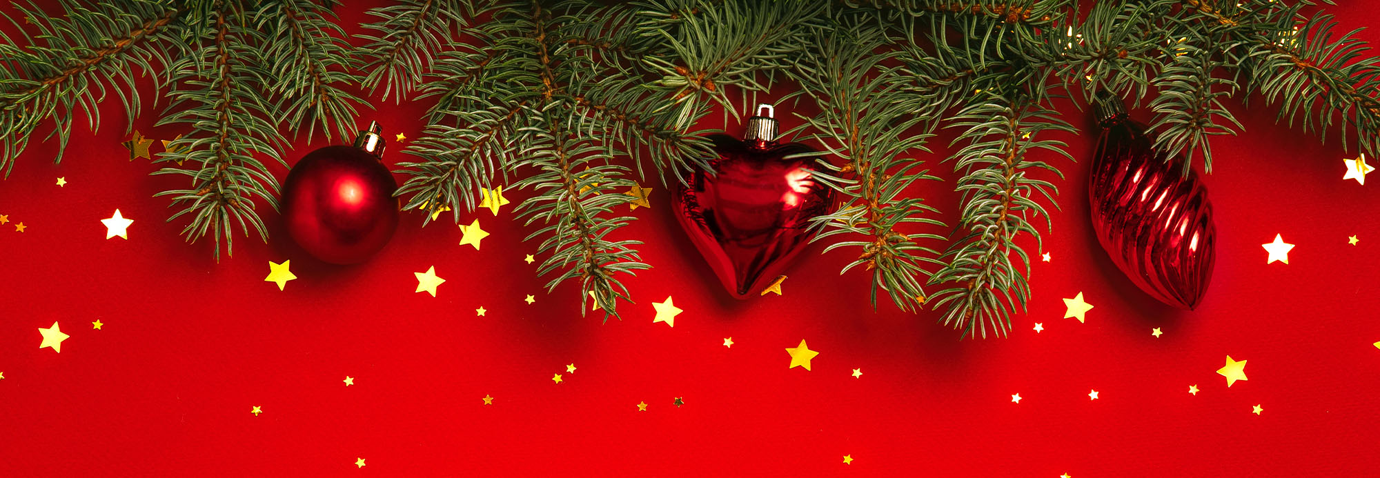 Red ornament on a Christmas Tress tree with red background and sparkle stars