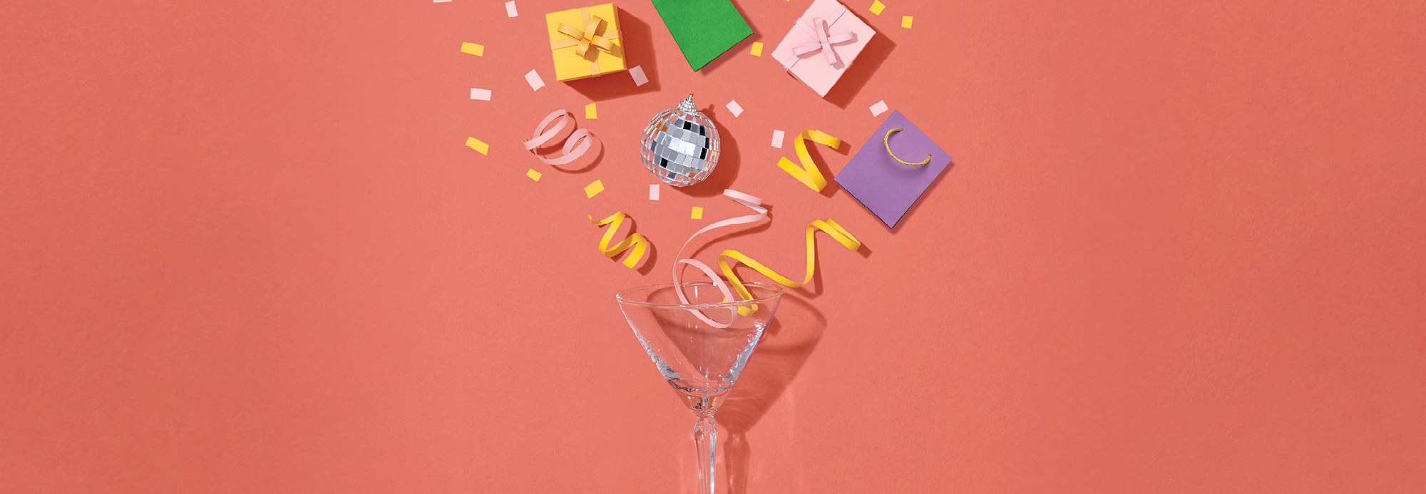 Confetti, a disco ball, shopping bags and colorful gift boxes popping out of a martini shell