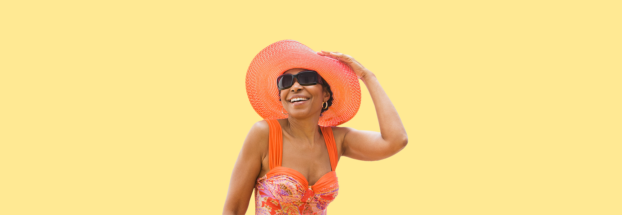 A woman wearing a sun hat, sunglasses, and a sundress