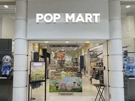 Front entrance of a POP MART store in a shopping mall, featuring colorful collectible toy displays and bright white signage.