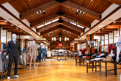 Interior of Portabella menswear store with wood-beam ceilings, mannequins in formal attire, and clothing displays arranged throughout the sales floor.