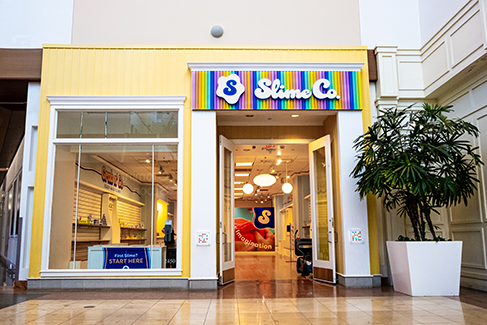 Colorful Slime Co. storefront in a shopping mall, featuring rainbow signage, bright interior décor, and hands-on slime-making activity areas.