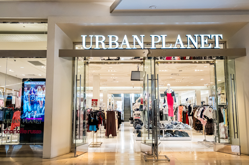 Storefront of Urban Planet clothing store in a shopping mall, featuring bright signage, glass entrance doors, and apparel displays visible inside.