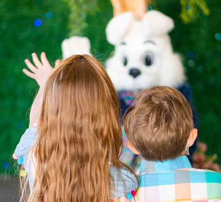 two children waving at the bunny
