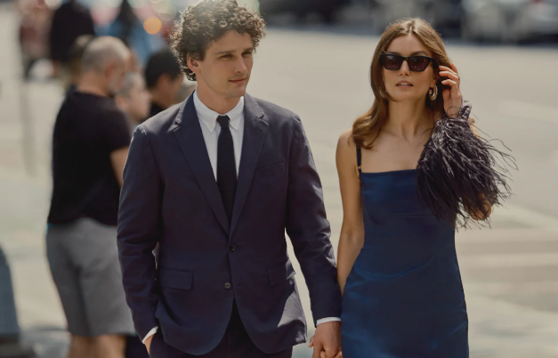 Man in navy suit and woman in blue formal dress walking to a wedding