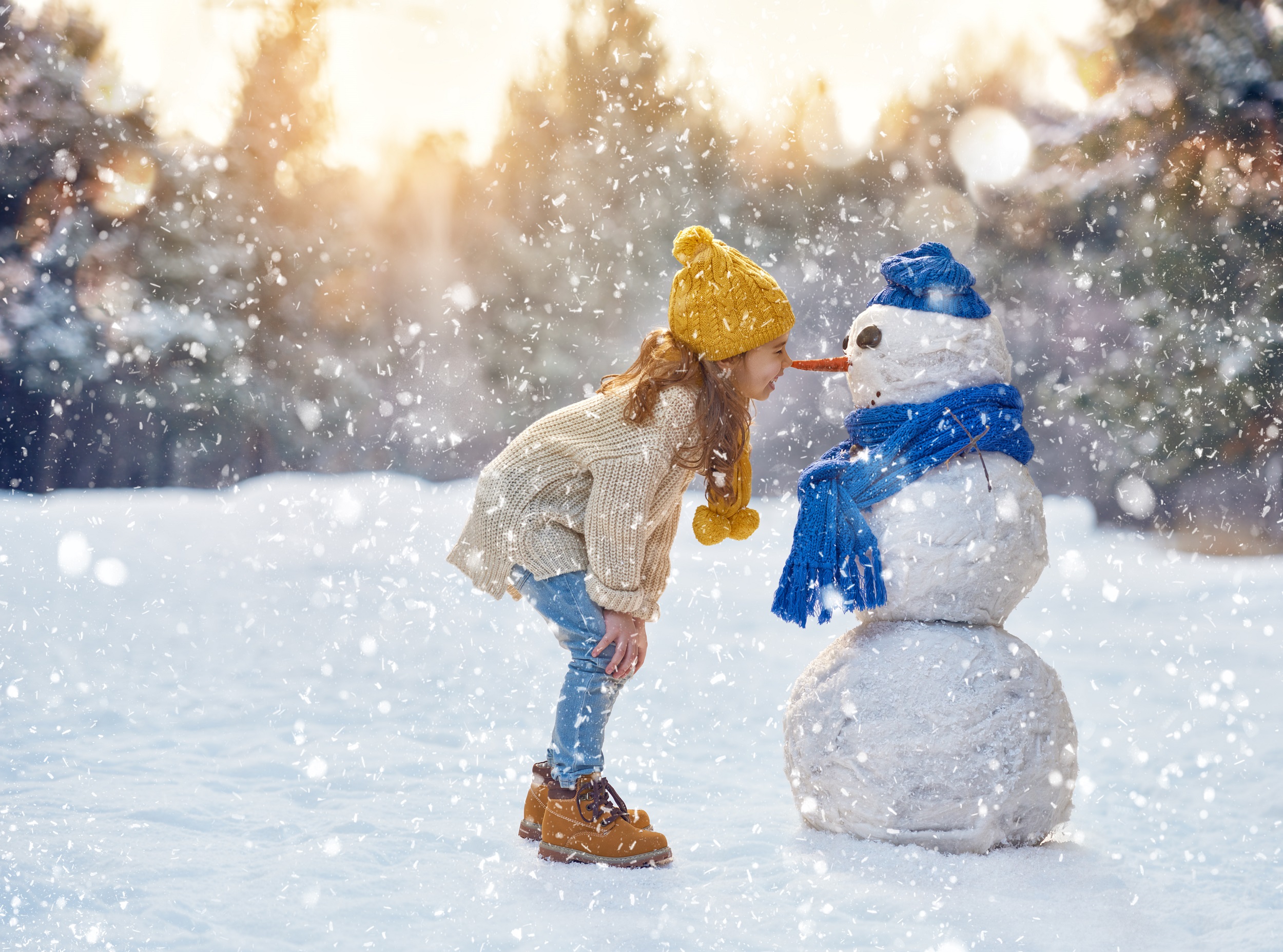 Little girl putting her nose up to a snowman