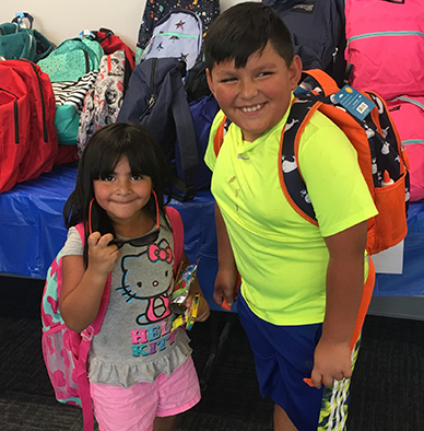 Boy and girl wearing backpacks and smiling