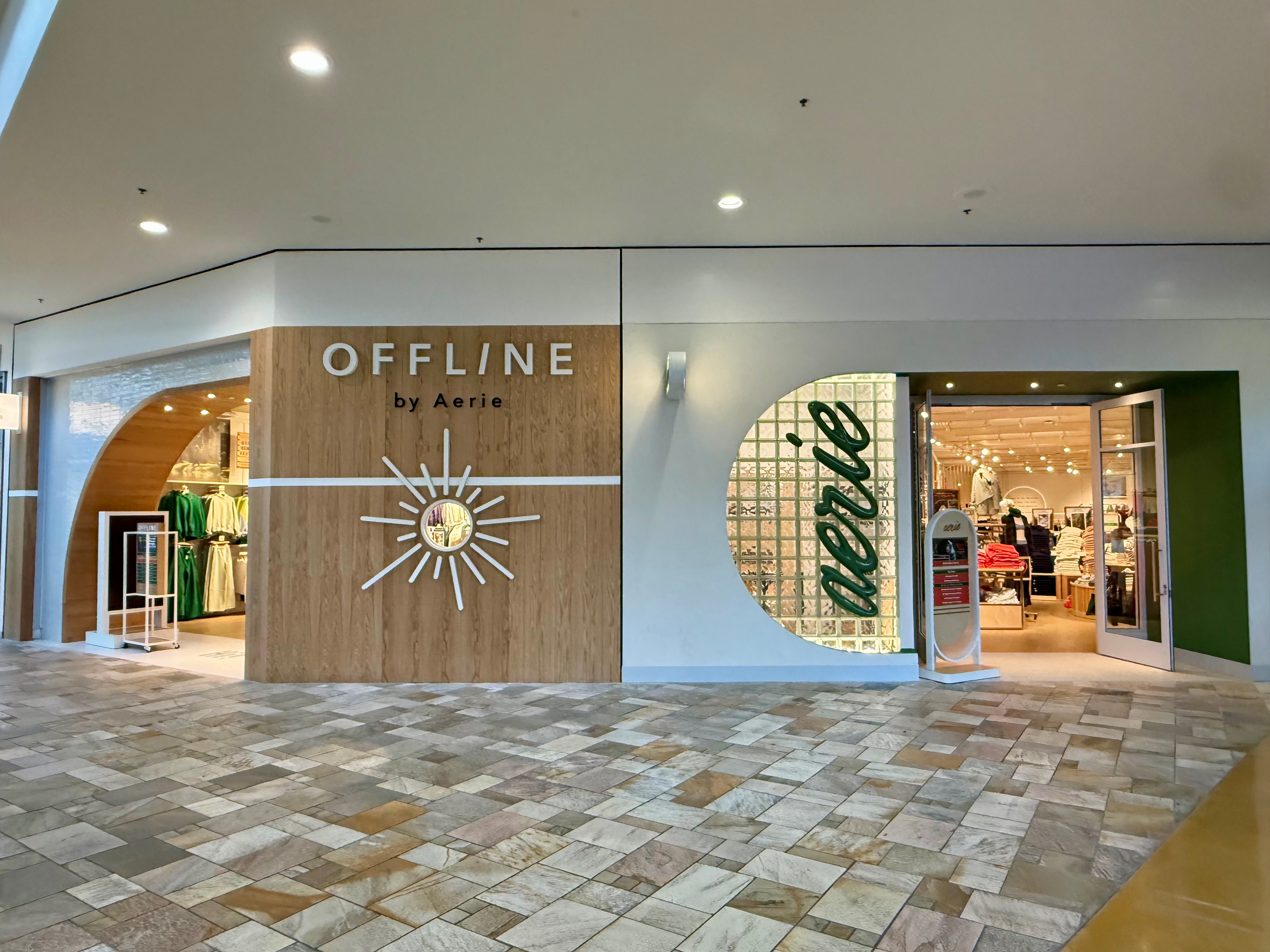 Offline by Aerie storefront with wood paneling, sunburst logo, and glass block feature wall; interior displays activewear and casual clothing