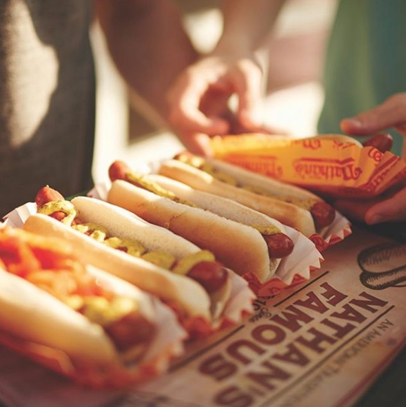 Five Hot Dogs with mustard lined up.  Wording states "Nathan's Famous"