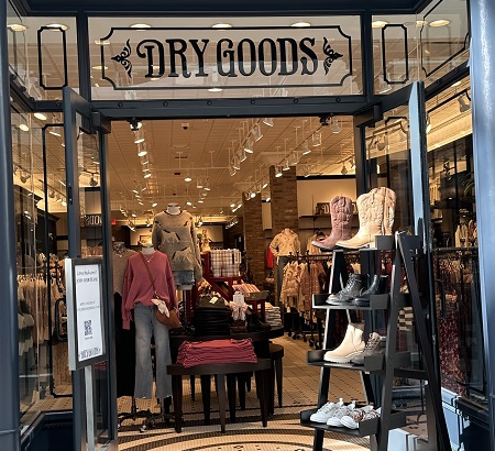 Front entrance of the Dry Goods Store with merchandise and a sign at the door