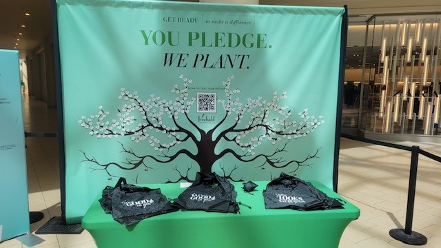 Banner with You Pledge We Plant heading with a tree and reusable bags on a table