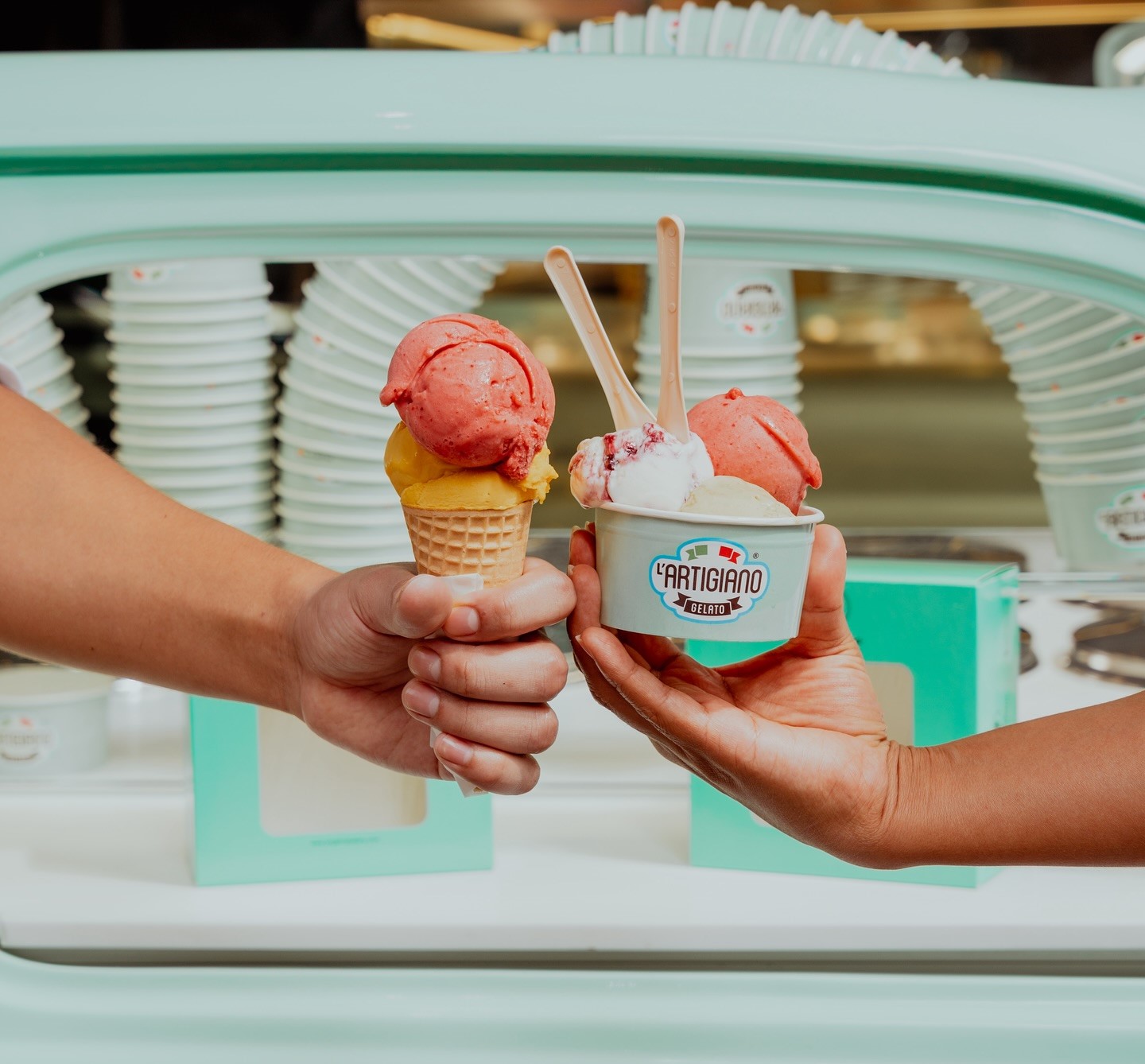 Two hands holding an ice cream cone and a cup of gelato