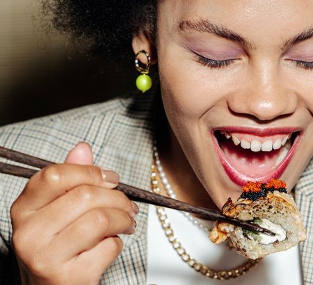 A woman eating sushi with chopsticks