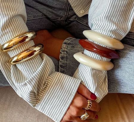 A woman wearing gold and wood bangles and gold rings