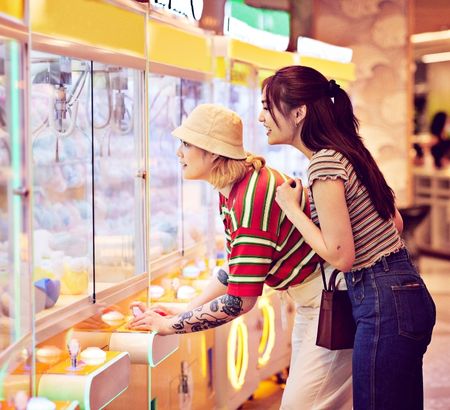 Two young women playing an arcade claw machine