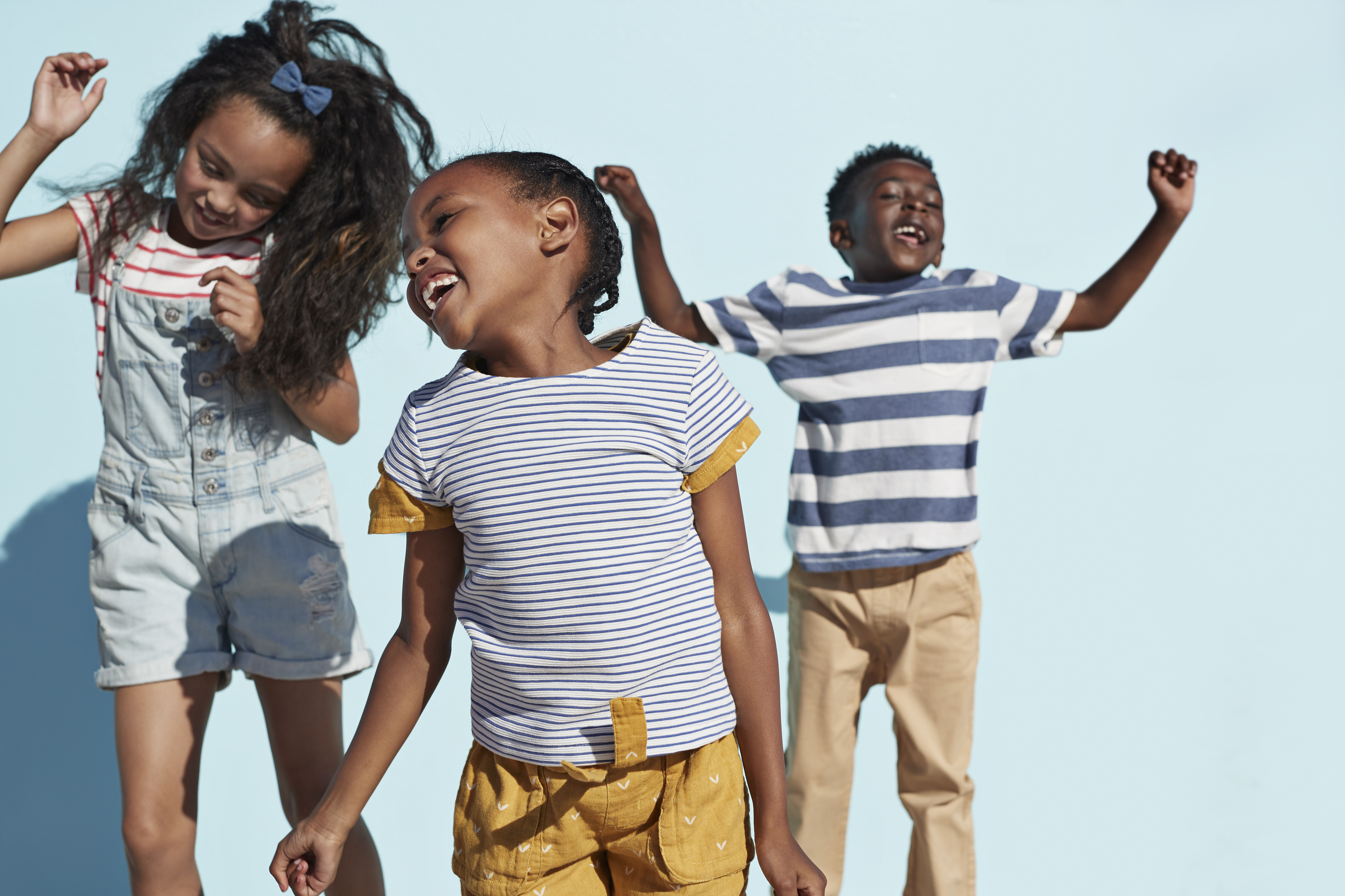 Three school-age kids jumping up and down, smiling