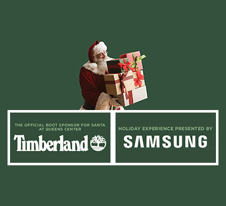 Santa holding a stack of presents. Timberland: The official sponsor for Santa at Queens Center. Holiday Experience presented by Samsung.