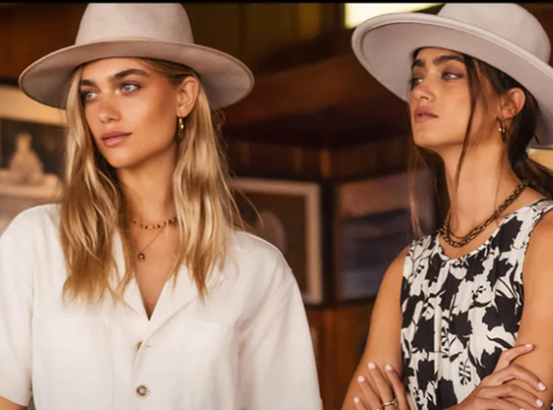 Women wearing flat brim hats in stylish clothing.
