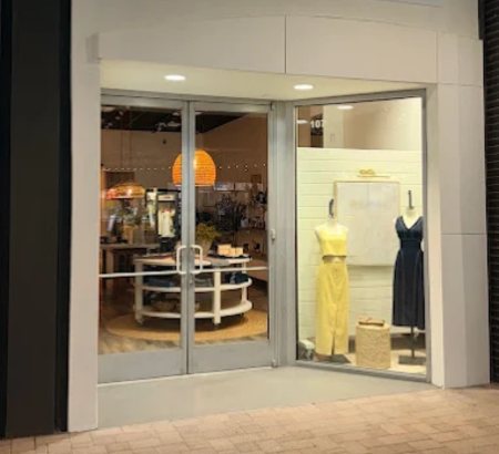 View of a storefront with women's apprel on display in the window and boho style hanging lights.