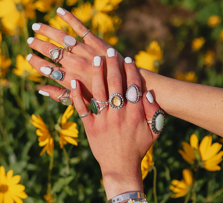 Assorted rings on hands in a sunflower field.