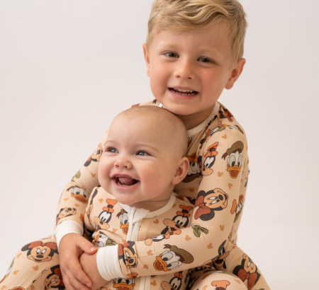 Little boy and baby girl wearing onesie pajamas and smiling for the camera.