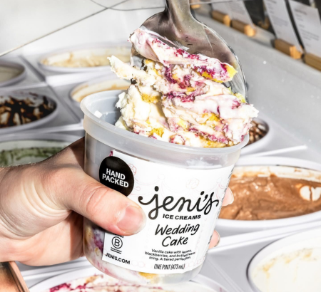 A hand holding a pint jar and filling it with ice cream.