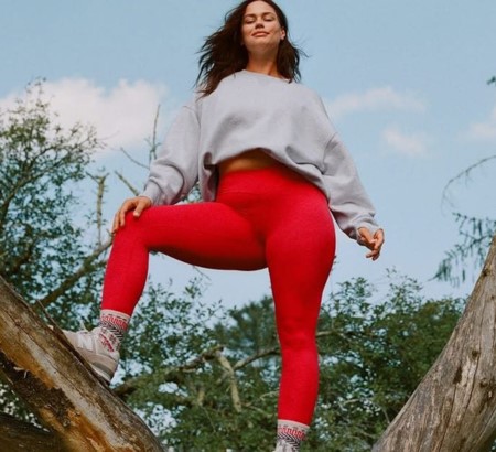 Woman wearing workout clothes standing on a tree posing.