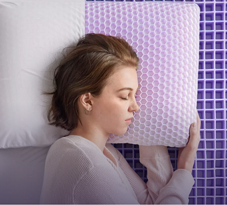 Person sleeping on their side, on a purple brand mattress and pillow.