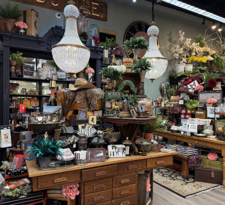 Home decor arranged on tables and shelves with chandeliers hanging from the ceiling.