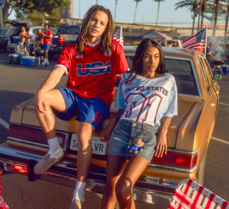 Boy and girl leaning against a classic car in a parking lot.