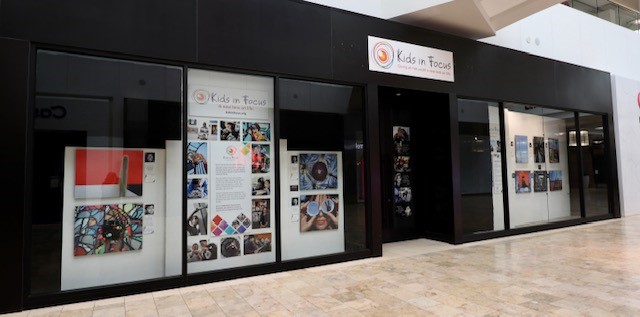 window display with photographs and signage explaining about Kids In Focus non-profit organization