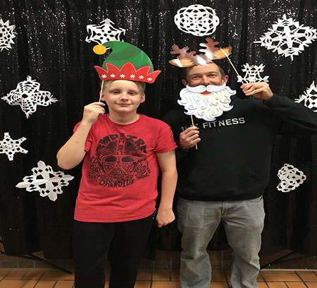 A Big and Little in a holiday photo booth with an elf hat and reindeer ears 