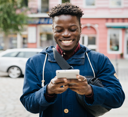 A young man smiling and looking at his phone.