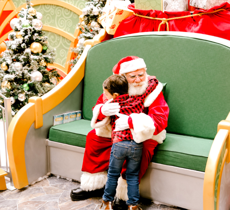 Girl sitting with Santa at Santa HQ set.