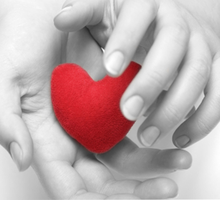 Black and white hands holding a red heart