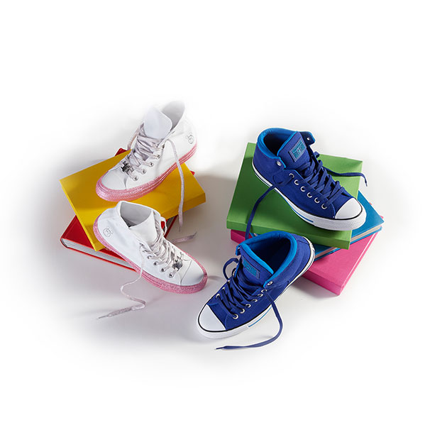 4 sneakers on two stacks of colorful books. 