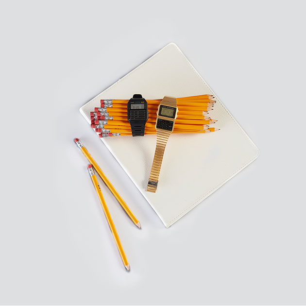 Retro calculator watches draped over a bundle of yellow pencils