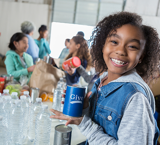 A school-age girl holding a donation container