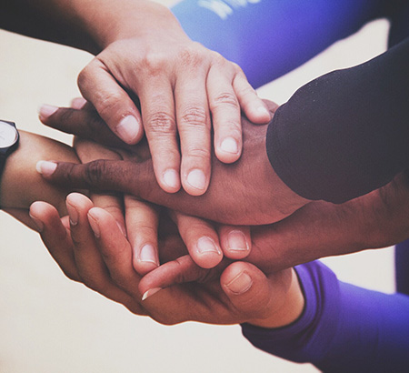 A team putting their hands together in a huddle