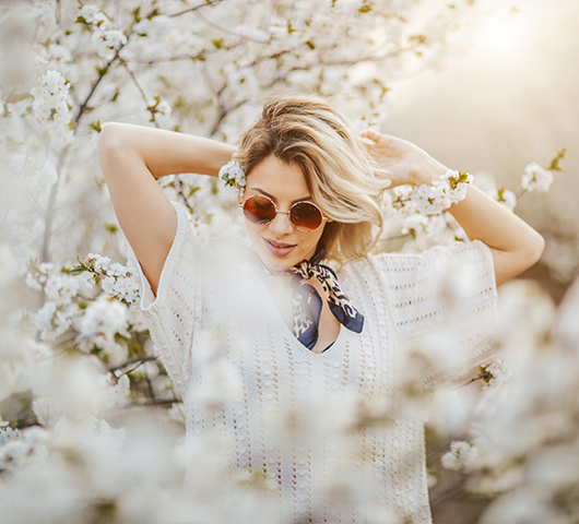 A woman modeling a breezy spring outfit in front of a cherry blossom tree