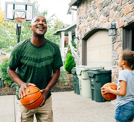 Father and daughter playing basketball in the driveway