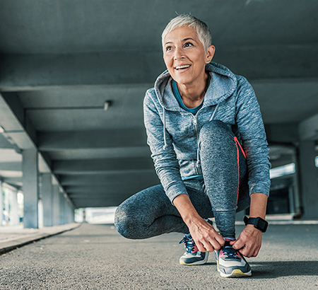 A senior woman wearing sneakers and running pants and jacket