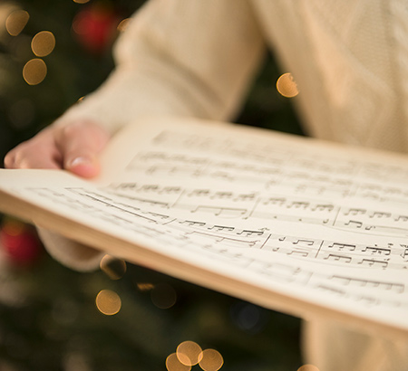 A person holding holiday sheet music