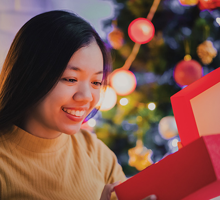 A smiling young woman opening up a present