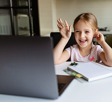 Little girl waving at her computer