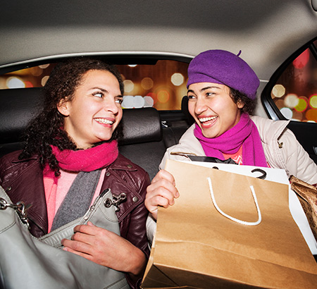 Two friends in the back seat of a car after an evening shopping trip