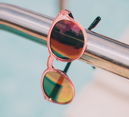 A pair of pink-framed sunglasses on a metal bar