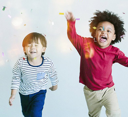Two kids jumping through confetti