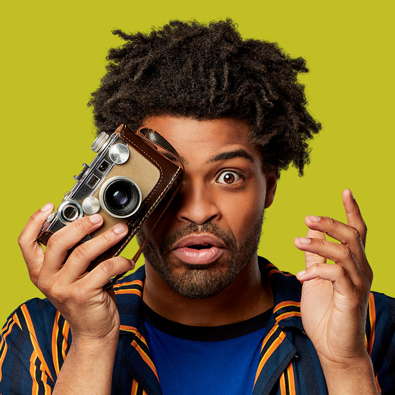 Man holding camera up to one eye with a surprised expression